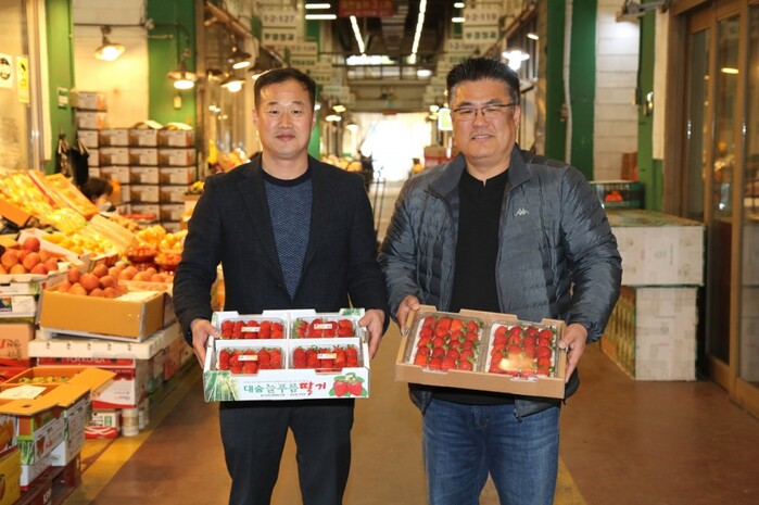 지난 20일 구리농수산물도매시장 만난 청송농장 이철희 대표(중도매법인)와 인터넷청과 주성진 정가수의사업부 이사(도매법인)가 스피루리나 딸기를 들어 보이고 있다.