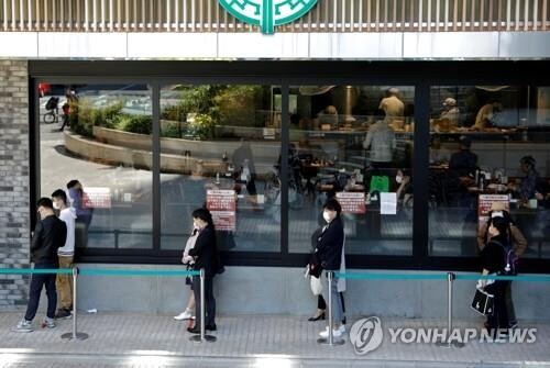 지난달 25일 도쿄의 한 가게 앞에 마스크를 착용한 시민들이 일정한 거리를 유지한 채 줄지어 서 있다. [도쿄= 로이터/연합뉴스]