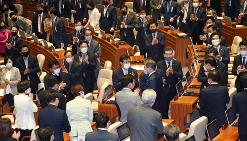 문재인 대통령이 16일 오후 국회에서 열린 제21대 국회 개원식에 입장하는 동안 더불어민주당 의원들과 검정색 마스크를 착용한 미래통합당 일부 의원들이 박수를 치고 있다. [사진= 연합뉴스]