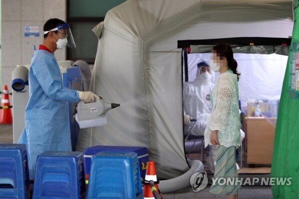 광주 서구보건소 마당에 마련된 선별진료소에서 시민이 코로나19 진단검사를 받기 전 겉옷을 소독하고 있다.[출처= 연합뉴스]